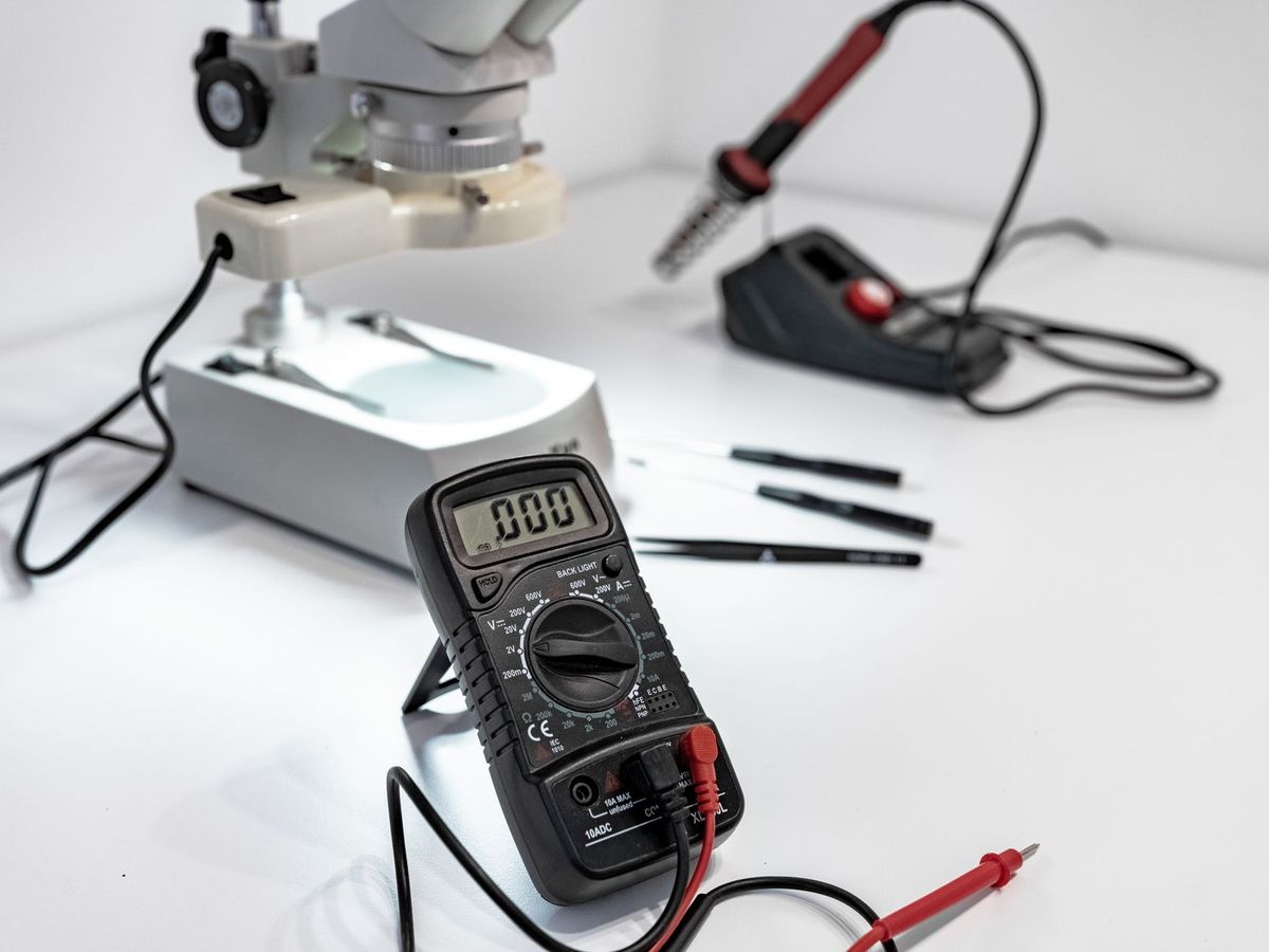 Beyaz masada mikroskop, havya ve dijital multimetre: elektronik prototip tezgâhı